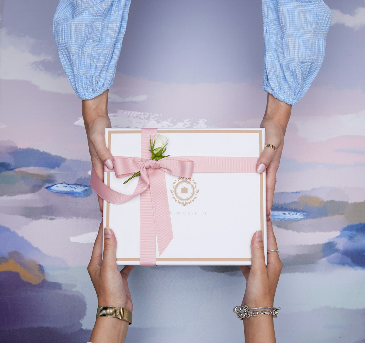 Two hands exchanging a beautifully wrapped gift box — Secret Santa and White Elephant gift ideas