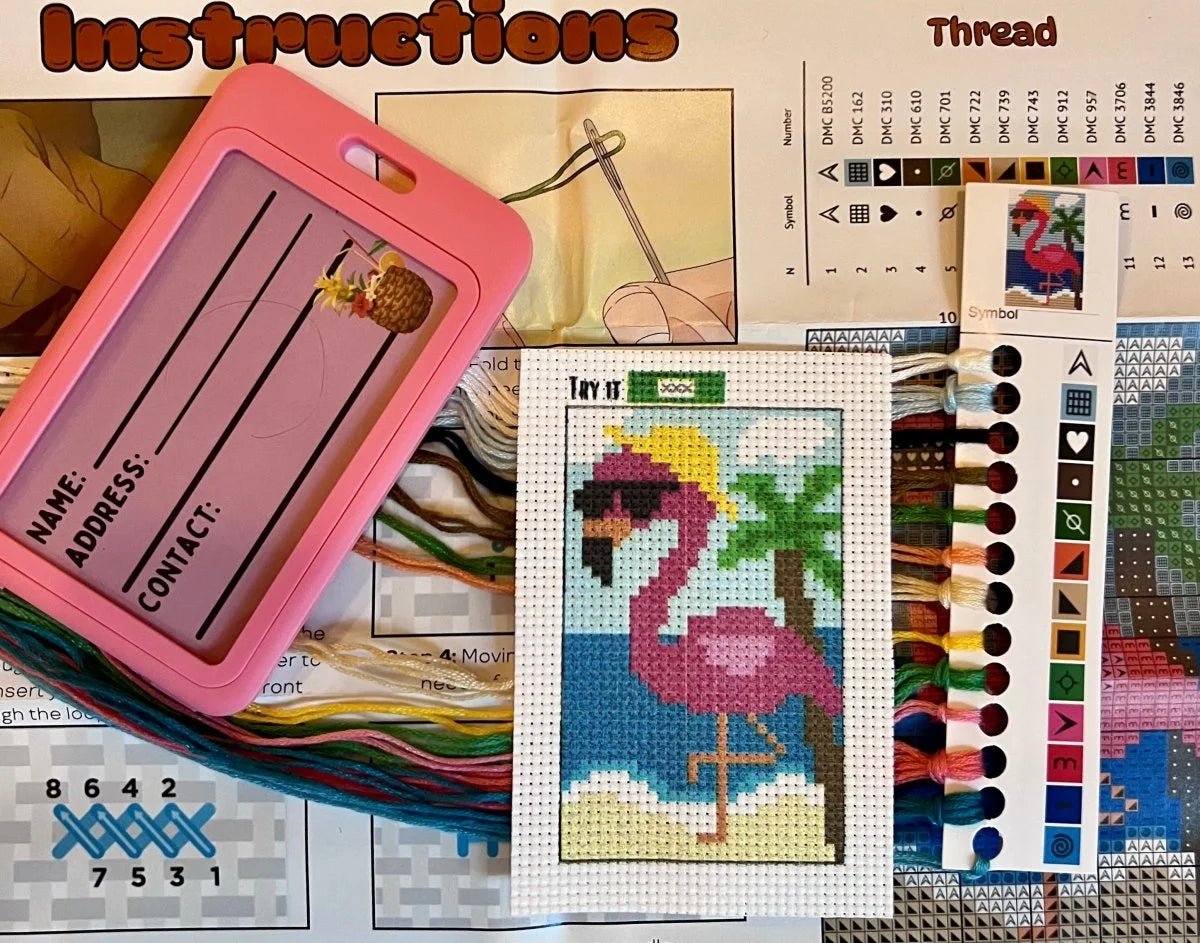 Cross-stitching materials including a pink frame, thread colors, and a flamingo design.