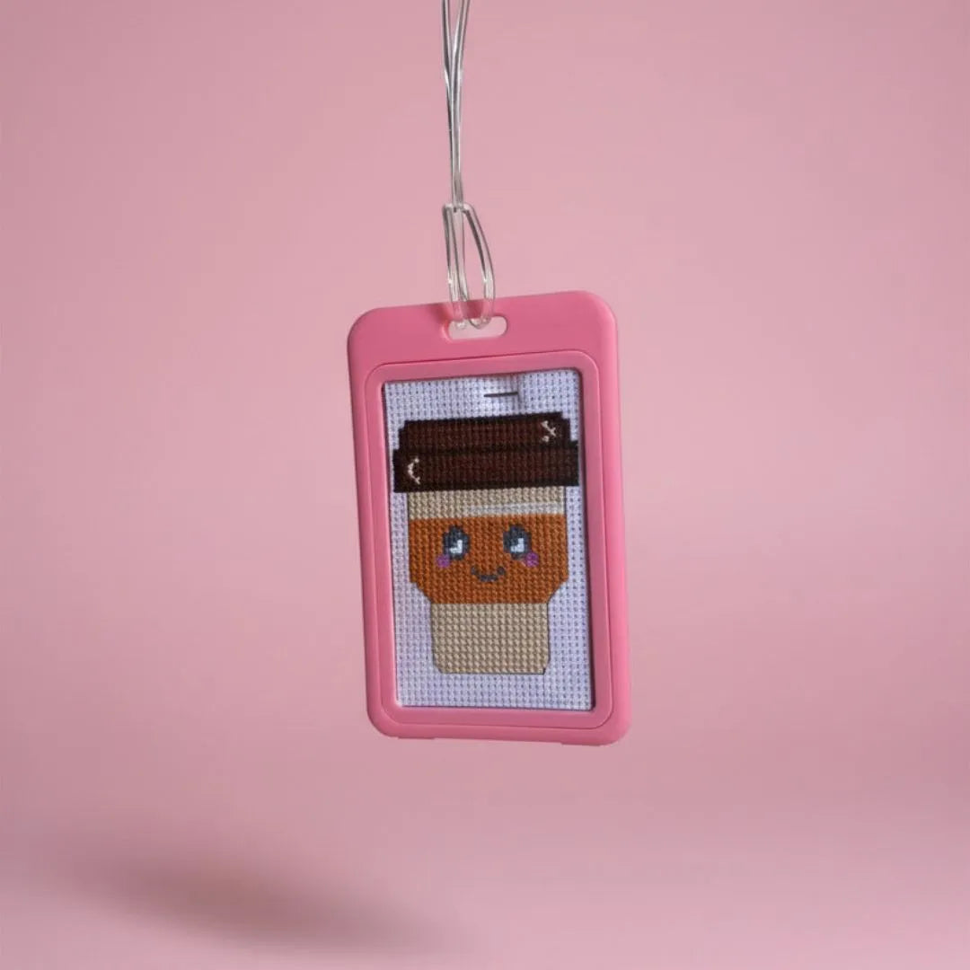 Cross-stitched character in a pink frame on a pink background