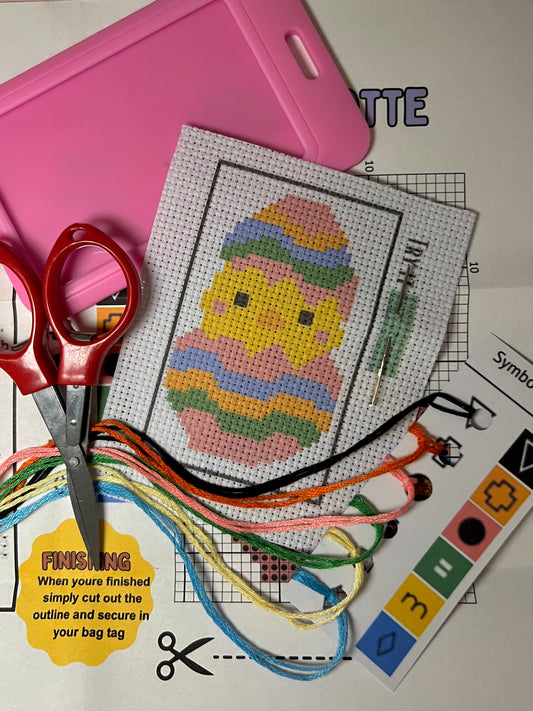 Cute Colorful Spring Chick mini cross stitch DIY luggage tag kit with a pink bag tag, luggage tag attachment, Scissors, needle and thread, stamped Aida fabric, color instructions