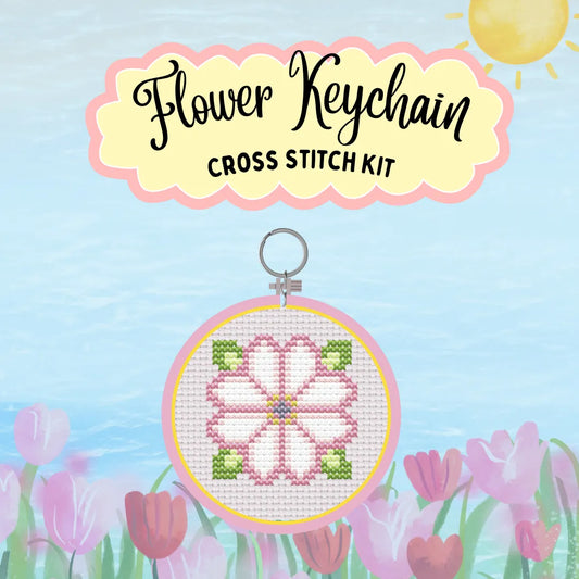 Cross stitch kit for a flower keychain with a blue sky and flowers in the background